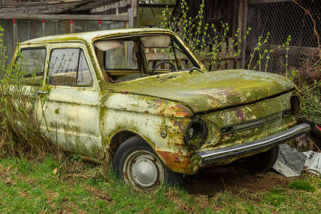 Abandoned Soviet ZAZ 968M car in rust and moss left by some household buildingのeditorial素材
