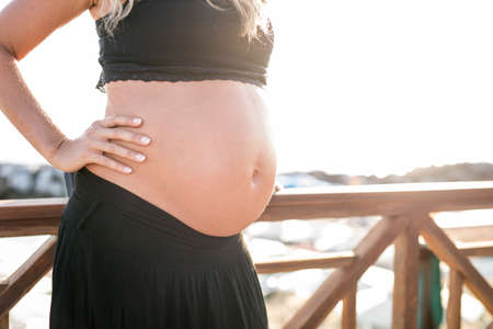 Pregnant woman on the beach, belly profile.