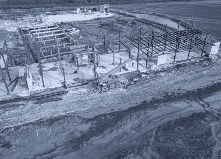 Aerial view of a construction site with heavy machinery for material lifting.