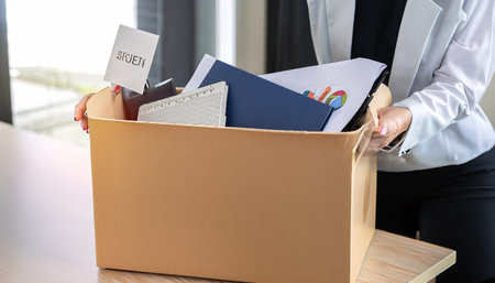 Close-up of businesswoman holding cardboard box with office supplies.の素材