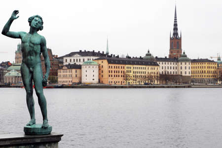 Statue outside stockholm town hall next to the river with swedish houses and court in the backgroundのeditorial素材