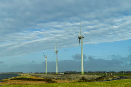 three Dutch windmills in a row for creating windenergy, next to the water in Zeeland, the...