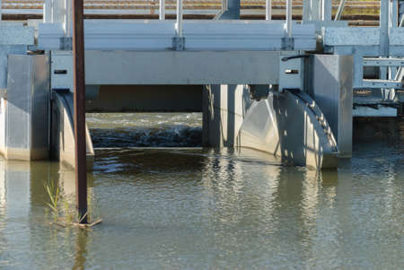 closeup of water flowing out of an irrigation control gate on a sunny dayの写真素材