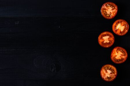Sliced tomatoes on dark wooden backgroundの写真素材