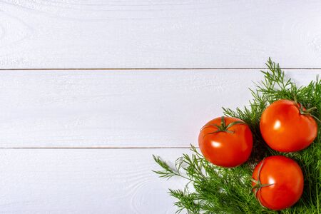 Three fresh tomatoes on white wooden background and fresh dillの写真素材