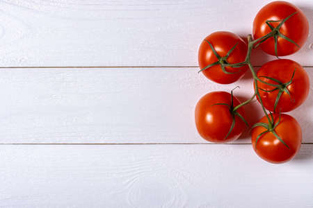 Five fresh tomatoes on white wooden backgroundの写真素材
