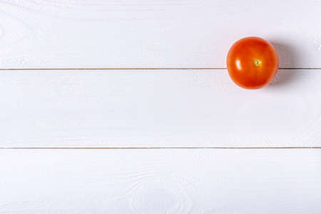 One fresh tomato on white wooden backgroundの写真素材