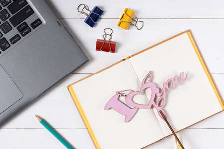 Laptop love sign and notepad on white wooden backgroundの写真素材