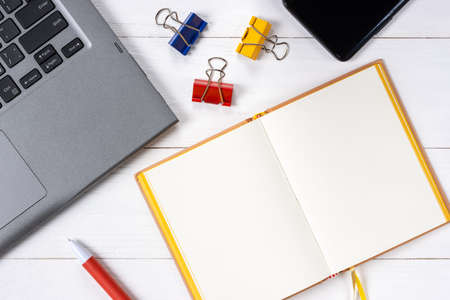 Laptop cellphone and notepad on white wooden backgroundの写真素材