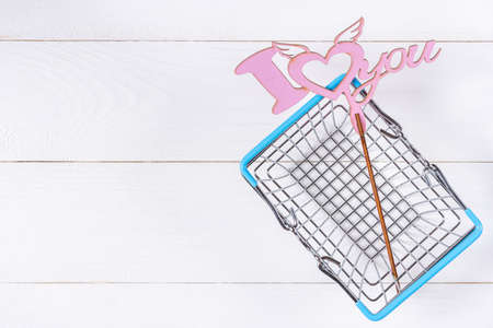 Empty shopping basket and love sign on white wooden backgroundの写真素材