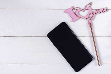Love sign and cellphone on white wooden backgroundの写真素材