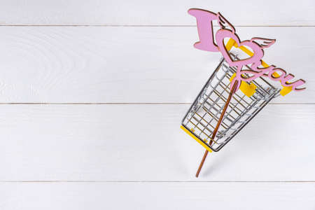 Love sign and shopping cart on white wooden backgroundの写真素材