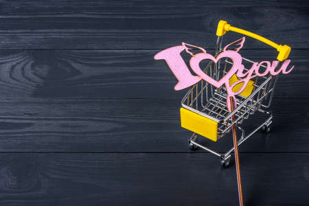 Shopping cart and love sign on a black wooden backgroundの写真素材