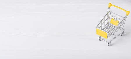 Empty shopping cart on a white wooden backgroundの写真素材