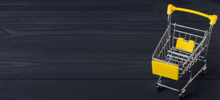 Shopping cart on a black wooden backgroundの写真素材