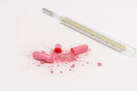 Glass thermometer scattered content of magenta pill tablet on whiteの写真素材