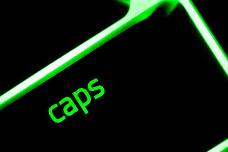 Green illuminated keyboard caps lock key closeup