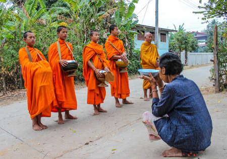 SURIN THAILAND-JANUARY 25  Unidentified  woman giving food to the monks and offering food to the monks  Thailandのeditorial素材