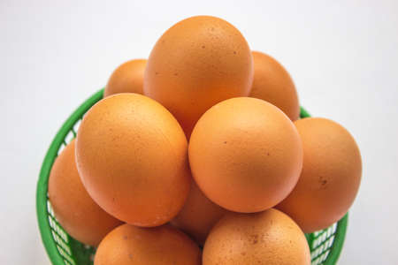 Brown eggs in the basket on white.