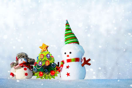 two snowmen one large and one small stand in the snowの写真素材