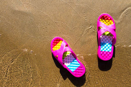 pink women's shoes on the sand near the waterの写真素材
