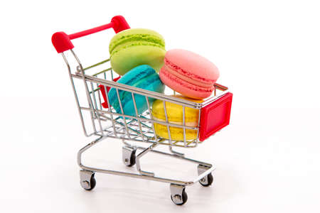 Collection of colorful French macarons lay in the purchase basket, on a white backgroundの写真素材
