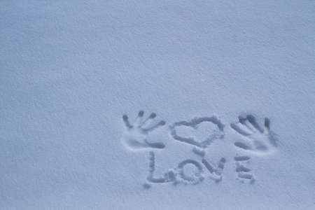 The inscription love in the snow, and a heart print