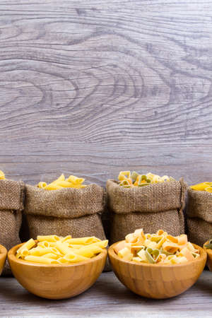 Various mix of pasta on wooden rustic background, sack. Diet and food concept. diversityの写真素材