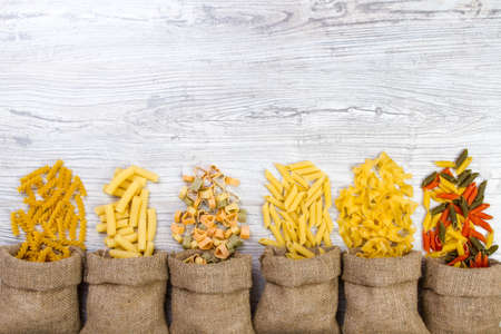 Various mix of pasta on wooden rustic background, sack. Diet and food concept. diversityの写真素材