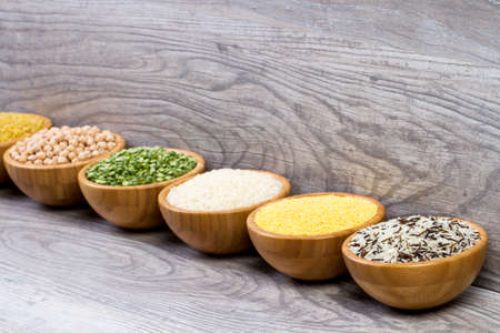 Set of cereals, peas, rice, millet, chickpeas sprinkled in bamboo bowlsの写真素材