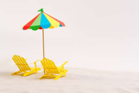 Made of paper umbrella and beach chair on the sand. White backgroundの写真素材
