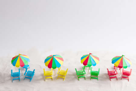 Four beach umbrella and deck chairs on the sand paper. White backgroundの写真素材