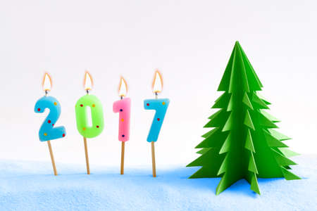 Burning candles in the snow with paper tree. Christmas background
