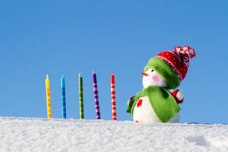 Bright snowman and festive candles on a winter background. Blue sky. White snow. Winter background.の写真素材