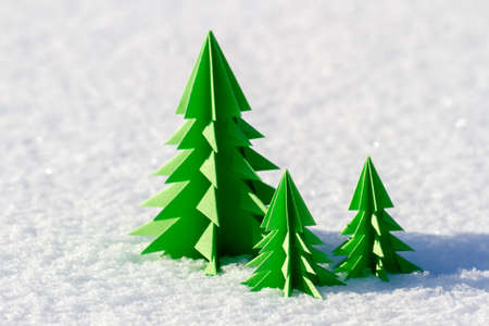 Trees of different colors of paper in the snow.の写真素材