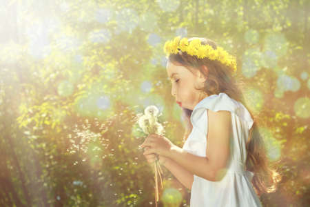 Little curly girl blowing dandelion.の写真素材