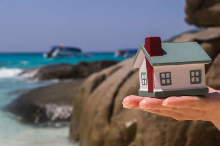 Toy houses keeps on hand against the blue sea.の写真素材