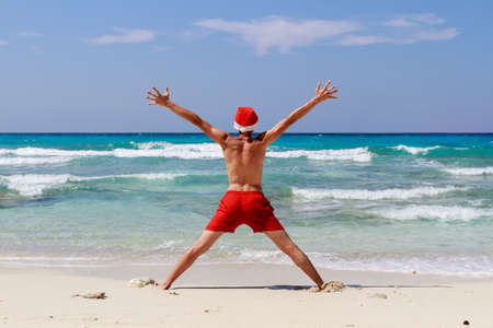 Christmas yoga man in red trousers and Christmas hat on the beach near the ocean. Similan Islandsの写真素材