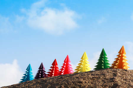 Seven paper Christmas trees stand in the sand against the blue sea. Similan Islands