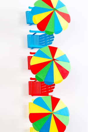 Bright umbrellas folding chairs are made of paper on a white backgroundの写真素材