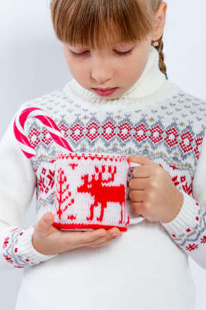 Girl in warm sweater is holding white mug in hands. Mockup for winter gifts design.の写真素材