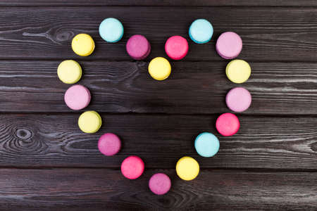 Bright almond cookies laid out on a dark wooden background in the form of heart.