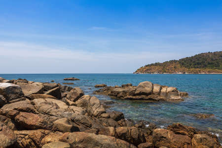 view from the rocky shore to the blue water on the island of Phuket Thailandの写真素材