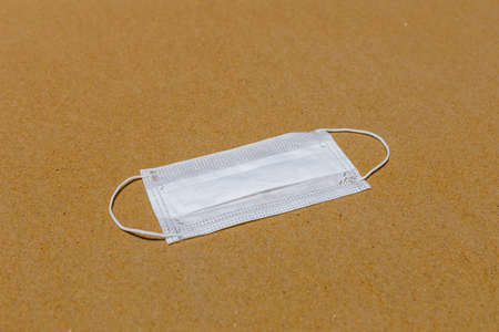 A protective medical mask is lying on the sand on the beach. coronavirus disease COVID-19 is dangerousの写真素材