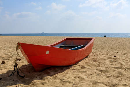 Tropical landscape. Red wooden boat on a sandy beach.の写真素材