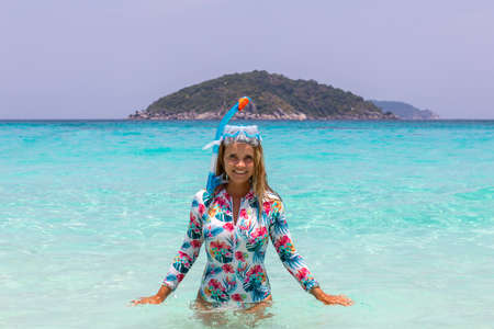 A young beautiful girl in a diving mask stands waist-deep in water. White sand. The Similan Islands.の写真素材