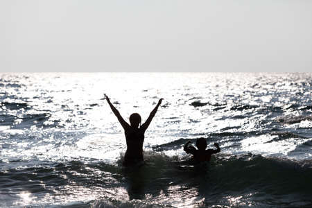 Silhouette of people jumping out of the water. Happy peopleの写真素材
