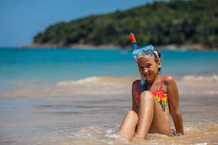Happy child girl in a mask on the beach in summerの写真素材