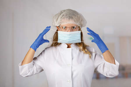 The doctor puts on a protective mask against viral infection.の写真素材