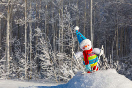 A smiling, happy snowman on skis surrounded by a winter landscapeの写真素材